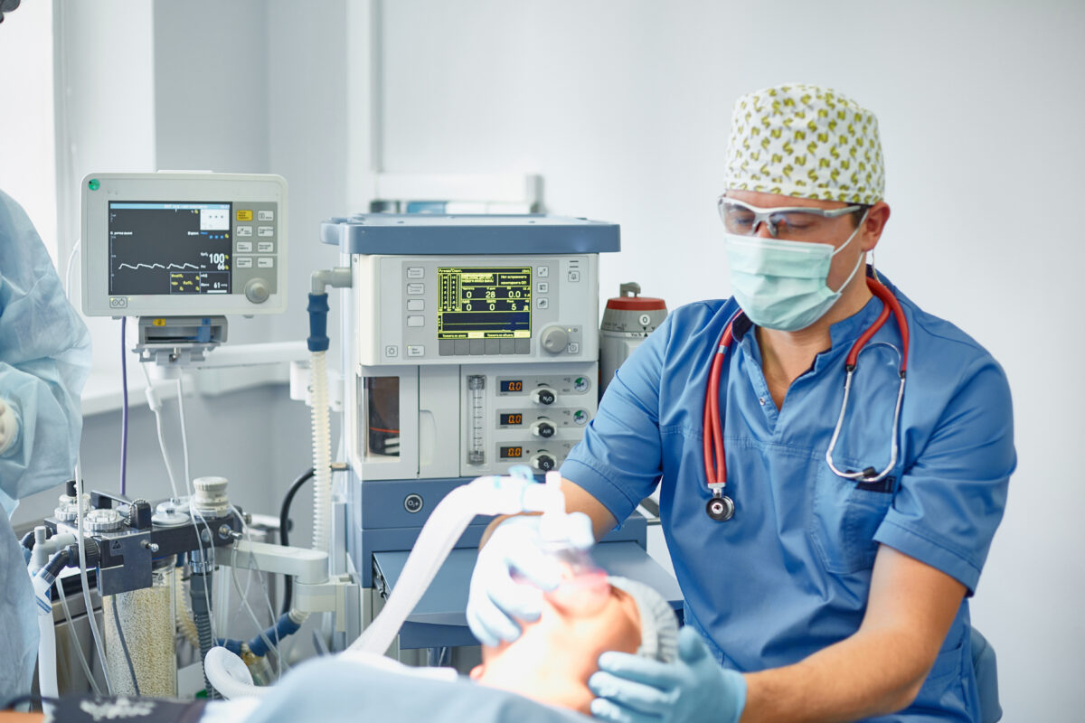 Several doctors surrounding patient on operation table during their work. Team surgeons at work in operating room.