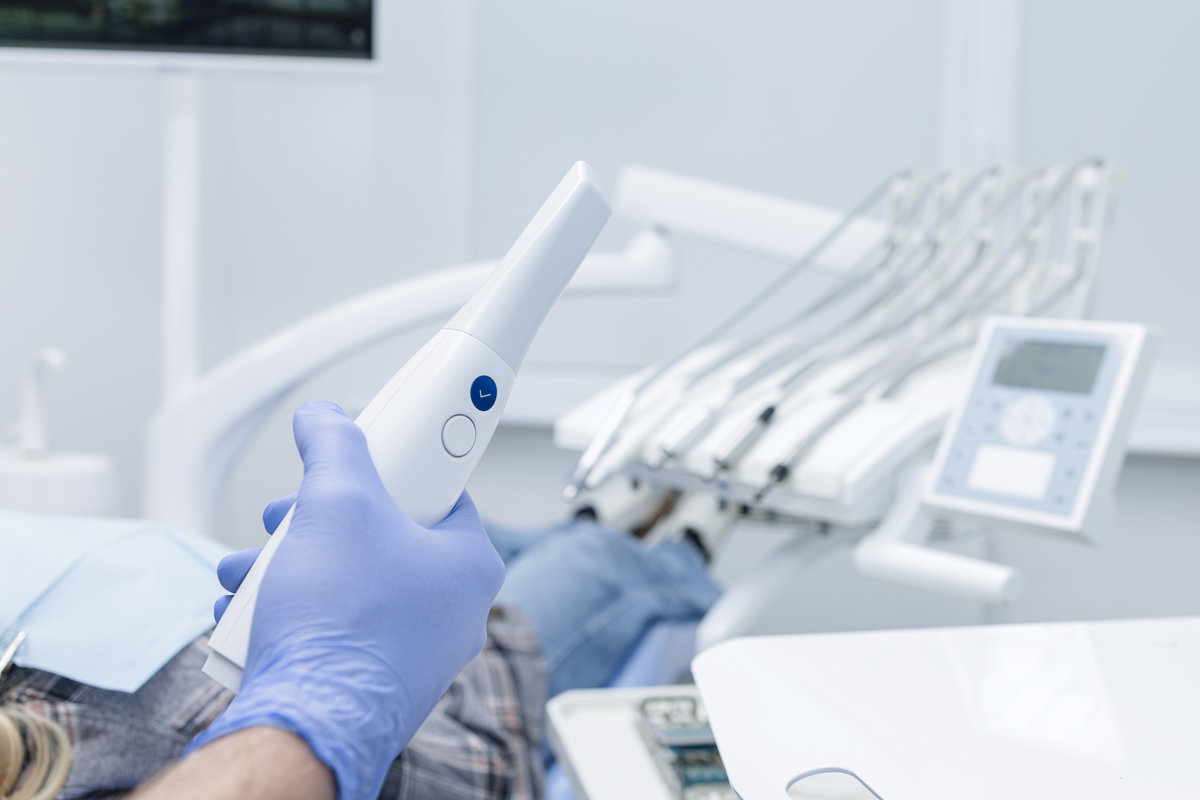 Dentist holds an intraoral scanner beside a patient, capturing a digital impression for CADCAM treatment planning in a modern clinic.