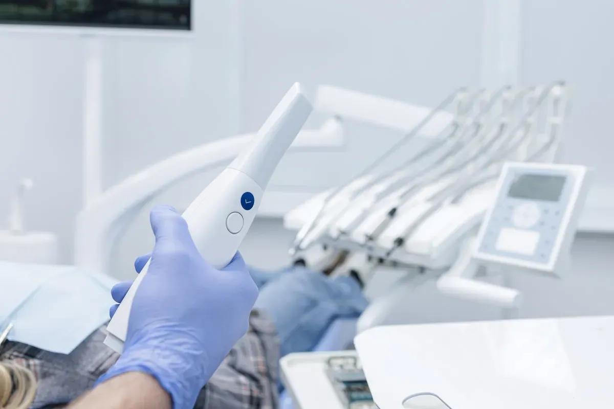 Dentist holds an intraoral scanner beside a patient, capturing a digital impression for CADCAM treatment planning in a modern clinic.